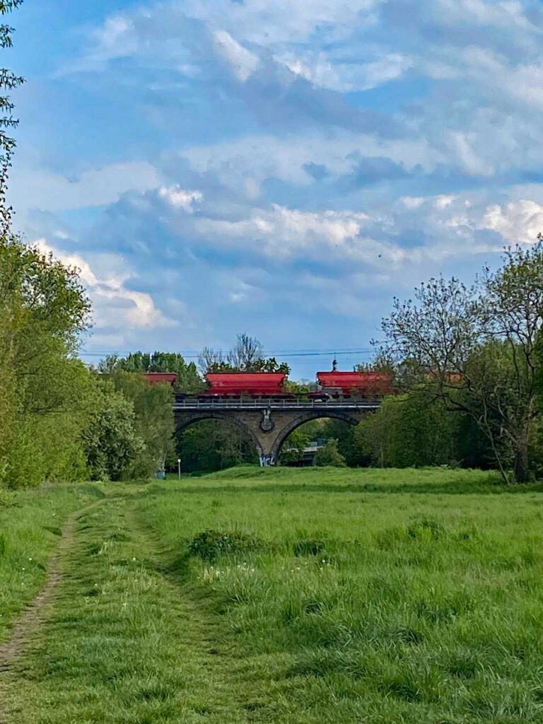 Eisenbahnbrücke mit roten Güterwagen. Von hinten nach vorne gelesen wird aus Tor - Rot